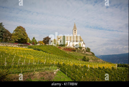 Vista autunnale della chiesa del villaggio idilliaco di Cortaccia. Cortaccia si estende sul lato soleggiato della strada del vino. Alto Adige - Italia Foto Stock