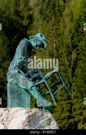 Il monumento alla sedia-maker, Gosaldo, Agordino, Dolomiti sullo sfondo di una foresta di abeti Foto Stock