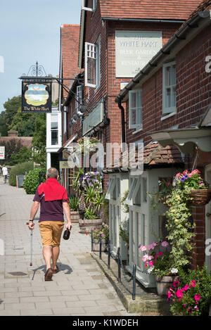 Un uomo cammina oltre il White Hart public house in Arundel, West Sussex, in Inghilterra. Foto Stock