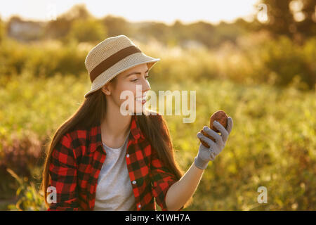 Ritratto di felice giovane donna giardiniere con patate in giardino. Giovane agricoltore la raccolta di patate. Il giardinaggio e agricoltura, raccolto autunnale concept Foto Stock