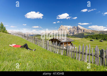 L'Europa, Italia, Alto Adige, Bolzano Dolomiti, escursionista in appoggio in un prato sull Alpe di Siusi Foto Stock