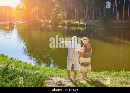 Coppia di anziani in piedi vicino all'acqua. Persone ammirando la vista parco. Foto Stock