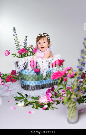 Splendido piccolo bambino si siede con un fiore. Foto Stock