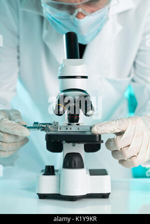 La ricerca scienziato che lavora con il modello di piastra su microscopio con molecola modello blu su sfondo di laboratorio con il fuoco selettivo Foto Stock