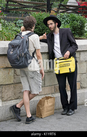 Un ebreo ortodosso giovane uomo in Union Square Park a New York, incoraggiando i ragazzi ebrei e gli uomini a don phylacteries e dire una preghiera, Foto Stock