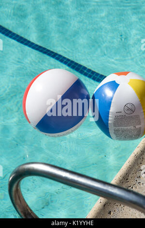 beachball colorato che galleggia in una bella piscina blu cristallo chiaro in una calda giornata estiva Foto Stock