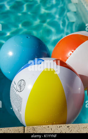 Palline da spiaggia colorate galleggiano in una bella piscina blu cristallo chiaro in una calda giornata estiva Foto Stock