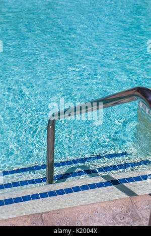 La luce del sole scintillante fuori acqua cristallina di una bella piscina.Una vista della piscina passi affascinando lo spettatore in acqua fredda in un giorno caldo Foto Stock