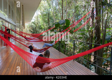 Persone in appoggio sulle amache rosso appeso sul Tunga Gallery, Inhotim Istituto Culturale, Brumadinho, Belo Horizonte, Minas Gerais, Brasile. Foto Stock