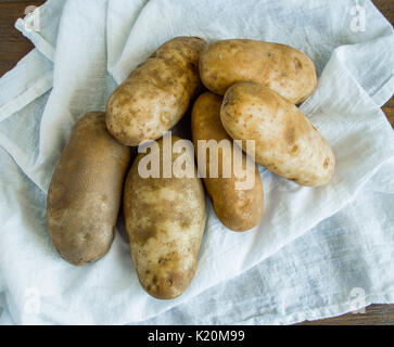 Still Life 6 patate impilati su un panno bianco visto dal di sopra Foto Stock