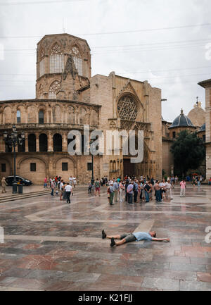 Valencia, Spagna - 3 Giugno 2016: giovane uomo giace sulla piazza di Santa Maria con i locali e i turisti a Valencia Città Vecchia di sera, Spagna Foto Stock