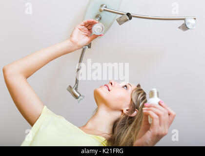 Pretty Woman cambiando lampadine a casa Foto Stock