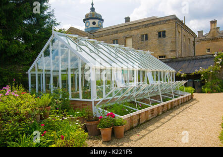 Serra con vasi di piante e vivacemente colorati fiori accanto a Rousham giardini, Oxfordshire, Inghilterra Foto Stock