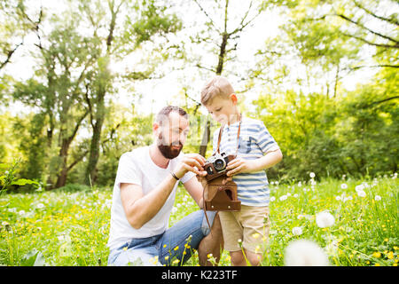 Giovane padre con piccolo ragazzo con telecamera in estate park. Foto Stock