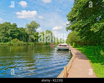 Una grande cabina cruiser sul fiume Bure, vicino a Wroxham, mentre una seconda barca viaggi a monte. Foto Stock