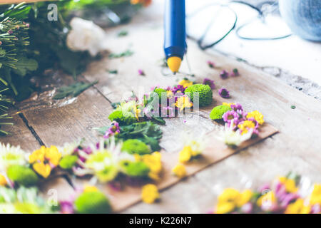 Fioraio effettuare decorazioni di fiori con lettere e colla. In interni luce naturale shot con piccole profondità di campo Foto Stock