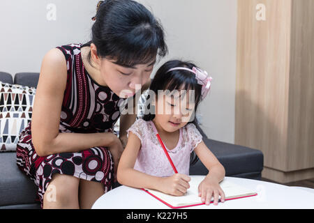 Asian madre cinese insegnamento figlia a fare i compiti a casa Foto Stock