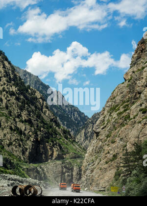 Due autocarri con cassone ribaltabile stanno guidando lungo la strada nella gola di montagna Foto Stock