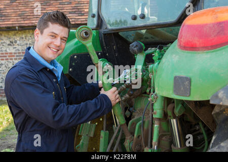 Ritratto di meccanico riparazione sul trattore Farm Foto Stock
