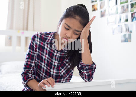 Sottolineato giovane ragazza seduta in camera da letto a casa Foto Stock