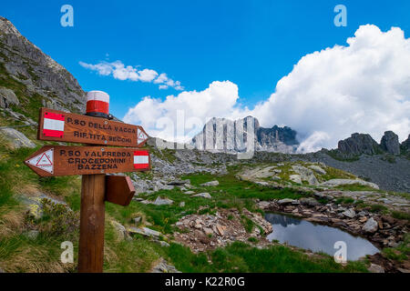 Gaver,Parco Adamello,Lombardia,Italia segni che indicano i percorsi e i rifugi nei pressi del lago di Vacce e il Rifugio Tita Secchi. Sullo sfondo il Monte Foto Stock