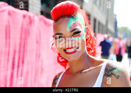 Migliaia di festaioli e spettatori godere di questo anno il carnevale di Notting Hill con un coloratissimo corteo. Una giovane donna tinto i suoi capelli di colore rosso brillante. Foto Stock