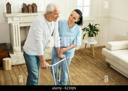 Piacevole uomo senior utilizzando apparecchiature a piedi Foto Stock
