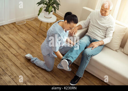 Nizza caregiver professionale tenendo la sua gamba pazienti Foto Stock