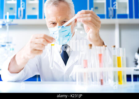 Fiducioso praticante aggiungendo liquido blu nel tubo Foto Stock