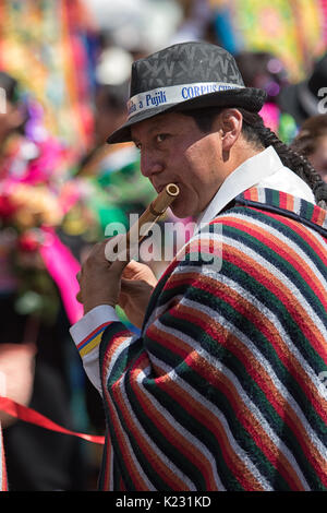 Giugno 17, 2017 Pujili, Ecuador: uomo indossando il tradizionale poncho suonare il flauto di bamboo presso il Corpus Christi parade Foto Stock