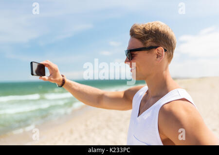 Uomo con lo smartphone a fotografare in estate spiaggia Foto Stock