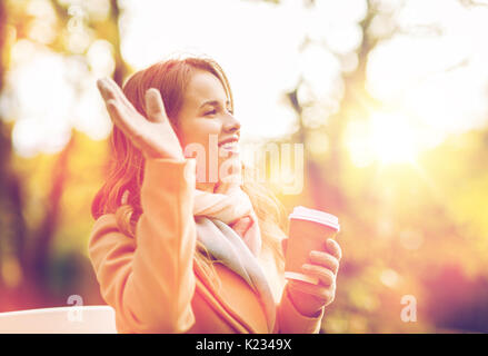 Felice giovane donna di bere il caffè in autunno park Foto Stock