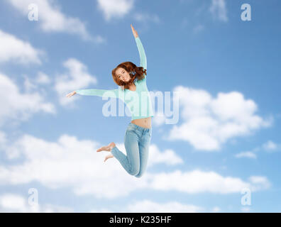 Sorridente giovane donna salti in aria oltre il cielo blu Foto Stock