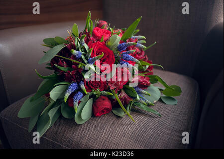 Brides bouquet di rose rosse prima del matrimonio risiede su un sfondo marrone Foto Stock