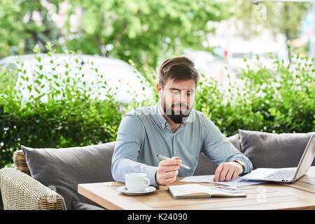 Imprenditore sorridente godendo lavorando in Cafe Foto Stock