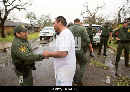 Resident Tony Garcia, destra, grazie U.S confine agenti Patrol dopo aver smontato gli alberi caduti e cancellati i detriti dalla sua casa dopo il passaggio dell uragano Harvey Agosto 28, 2016 in Rockport, Texas. Tiny Rockport fu quasi completamente distrutta dall'uragano Harvey come è venuto a terra come una categoria 4 tempesta con 130mph venti. Foto Stock