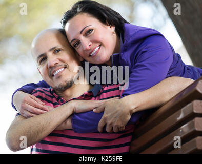 Ritratto di anziani felice coppia seduti insieme sul banco e la tenuta di ciascun altro Foto Stock