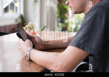 Giovane uomo caucasico controllo social news update e messaggio sul telefono intelligente al cafe. avviare piccoli imprenditori lavora con telefono mobile a Foto Stock