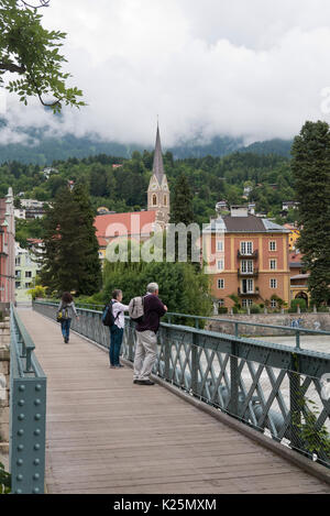 Un giovane in piedi su un ponte in acciaio ammirando il panorama di Innsbruck, in Austria. Foto Stock