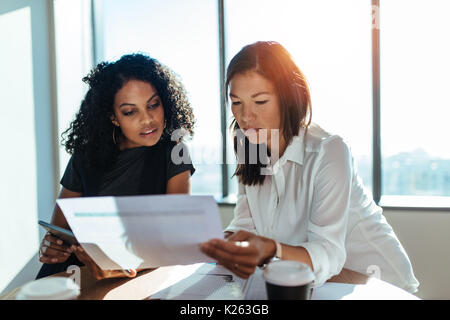 Imprenditrici avente una riunione seduta a tavola in ufficio. Due giovani imprenditori a discutere di questioni aziendali. Foto Stock