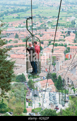 Europa,l'Italia,Umbria, Gubbio. Due persone in una macchina di cavo con la città di Gubbio in background Foto Stock