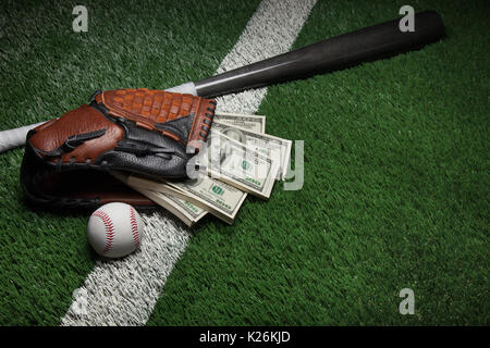 Un guanto da baseball pieno di centinaia di dollari su un campo con una mazza e sfera Foto Stock
