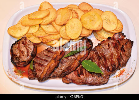 Piastra con patate fritte e grigliate di carne Foto Stock