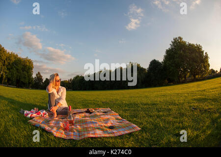 Una donna di mezza età da solo su un tappeto come il sole tramonta Foto Stock