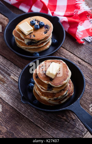 Pancake con mirtilli freschi conditi con il burro in padella in ghisa è servita per il brunch romantica sul tavolo rustico Foto Stock