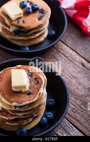 Pancake con mirtilli freschi conditi con il burro in padella in ghisa è servita per il brunch romantica sul tavolo rustico Foto Stock