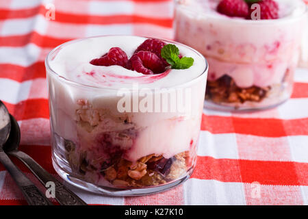 Lampone scherzare con croccante di avena tostati e frutta secca, eton mess style granola dessert servito sul vecchio stile tovagliolo rosso Foto Stock