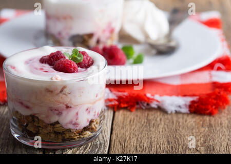 Lampone scherzare con croccante di avena tostati e frutta secca, eton mess style granola dessert servito sul vecchio stile tovagliolo rosso Foto Stock