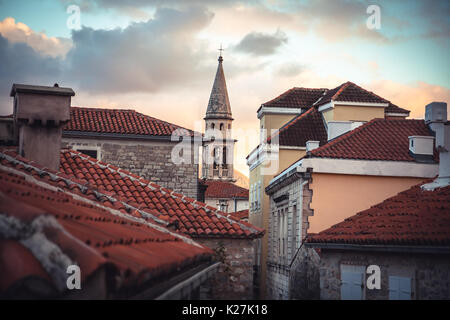 La vecchia Europa dello skyline della città con orange i tetti di tegole e la torre di fronte tramonto spettacolare Sky con mobili antichi di architettura in Europa città di Budva Montenegro Foto Stock