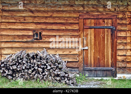 Log Cabin parete con piccola finestra, porta e piccola pila di legno Foto Stock